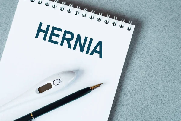 Masanın üzerinde termometre ve kalem olan boş bir defter. HERNIA metni.