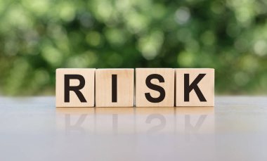 Tahta bloklara yazılan RISK kelimesi. Metin siyah harflerle yazılır ve masanın ayna yüzeyine yansıtılır. Tasarımınız için iş kavramı.