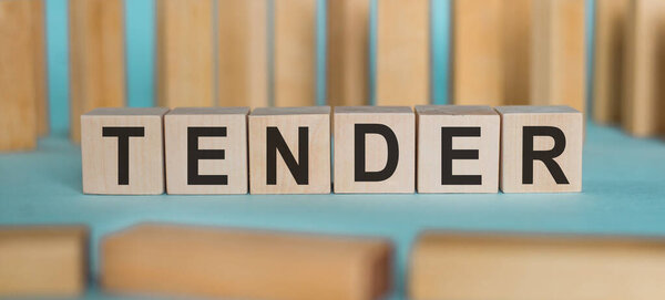 ТЕНДЕР. Слово, написанное на деревянных блоках на голубом фоне.