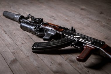 Tahta arka planda izole edilmiş susturuculu Kalaşnikov saldırı tüfeği