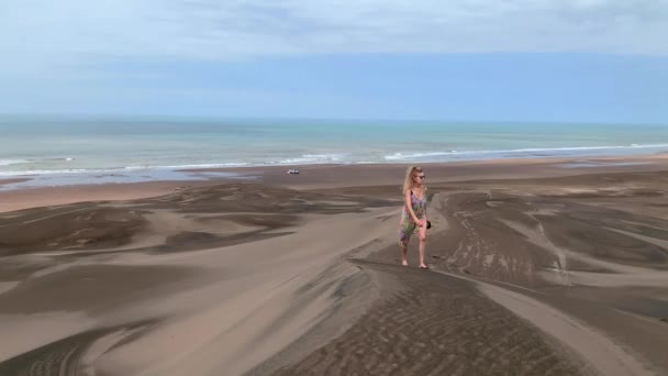 Mature woman walking along the top of a medano with sunglasses and smart phone in hand. — Stok video