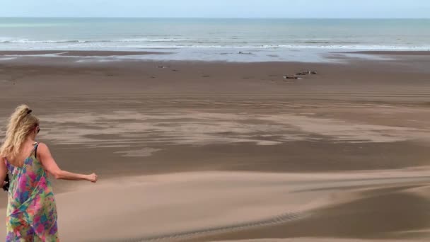 Mulher adulta andando por um grande medano com a praia e o mar na frente — Vídeo de Stock