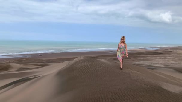 Video van een volwassen vrouw met een zonnebril die naar de top van de medano loopt en zijwaarts naar de camera loopt — Stockvideo