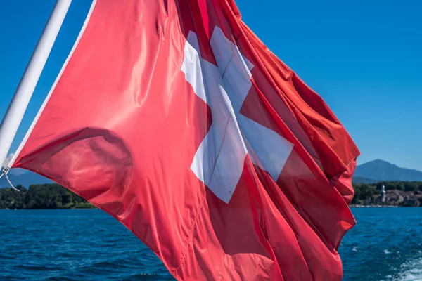 日内瓦湖上在风中飘扬的瑞士国旗的肖像照片 — 图库照片
