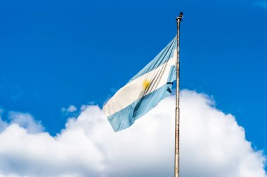 Arjantin bayrağı bulutlu bir gökyüzünde bayrak direğinde dalgalanıyor. Arjantin 'in vatansever amblemi.