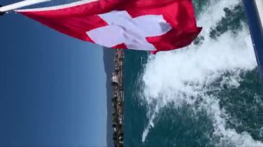 İsviçre bayrağının Geneva Gölü 'nden sonra rüzgarda dalgalanan dikey videosu.