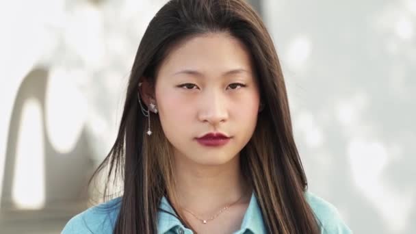Sevimli, sakin, ciddi, Çinli genç bir kadının portresi kameraya duygu ile bakıyor. — Stok video