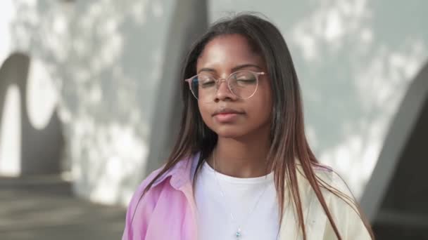 Sakin, Afro-Amerikalı, gözlüklü ve kameraya bakan genç bir kadının portresi. — Stok video