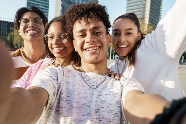 Ryhmä onnellisia monietnisiä teini-ikäisiä ystäviä ottaa selfien yhdessä kaupungissa — kuvapankkivalokuva