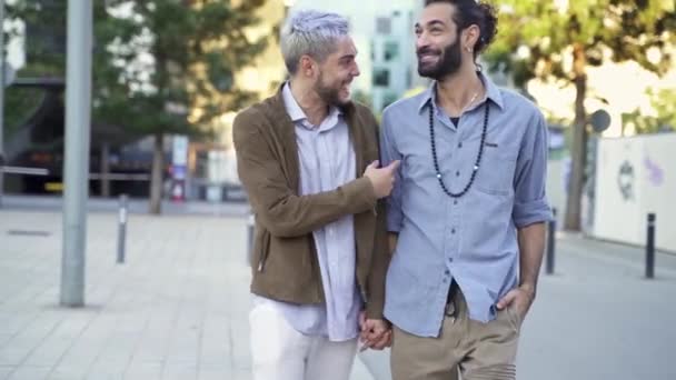 Felice coppia gay divertirsi, parlare e camminare insieme tenendosi per mano in città — Video Stock