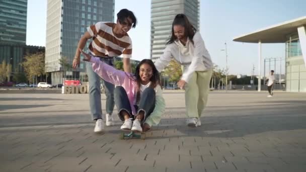 ティーン多人種のアジア人とラテン人の友人は、現代都市でスケートボードで一緒に楽しみを持っています — ストック動画