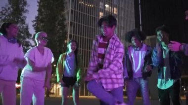 Genç Asyalı adam sokak partisinde çok kültürlü arkadaşlarıyla dans ediyor. Çılgınca bir kutlamada eğleniyorlar. Geceleri şehirde dans figürleri sergiliyorlar.