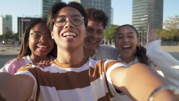 Азиатский мальчик делает селфи или делает видеозвонок со счастливыми друзьями в городе — стоковое видео