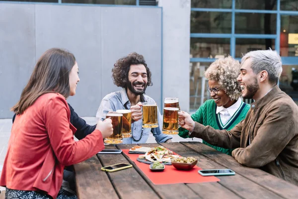 Ryhmä onnellisia monirotuisia ystäviä paahtamassa olutta juhlimaan töiden tai syntymäpäivän jälkeen. — kuvapankkivalokuva