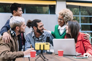 Mutlu dijital içerik yaratıcıları dışarıda mikrofon ve laptop kullanarak canlı yayın yapıyor. Yaratıcı blog yazarları birlikte eğleniyor.