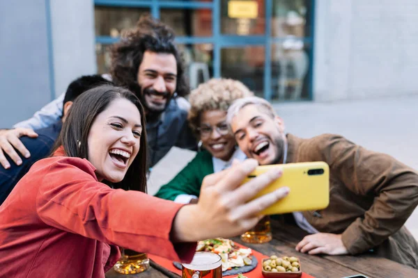 Jonge vrouw het nemen van selfie foto van de viering met vrienden in de buitenlucht bar om te delen op sociale media — Stockfoto