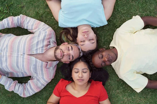 De jeunes amis détendus couchés ensemble sur de l'herbe verte, les yeux fermés, rêvant ensemble, dormant avec une connexion émotionnelle. Peuple hispanique latin — Photo