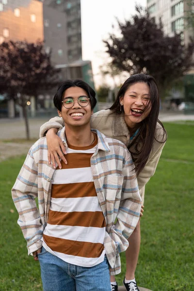Onnellinen aasialainen teini ystäviä syleilee ja pitää hauskaa yhdessä, yllään trendikkäitä vaatteita, positiivisia tunteita — kuvapankkivalokuva
