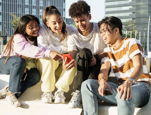 En gruppe glade tenåringsvenner som bruker mobilappen sin til å dele morsomme øyeblikk – stockfoto