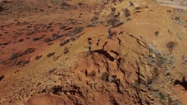 オーストラリアの砂漠の山の丘の上で楽しいダンスをしている面白い若い旅行者のカップル。ロードトリップの自由の冒険 — ストック動画