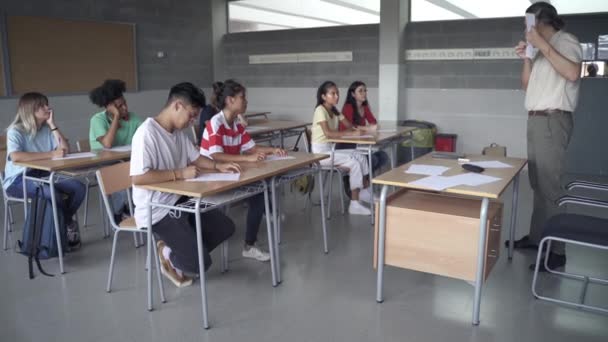 Καθηγητής που εξηγεί την άσκηση των εξετάσεων στην τάξη του λυκείου σε μια ομάδα πολυεθνικών εφήβων μαθητών — Αρχείο Βίντεο