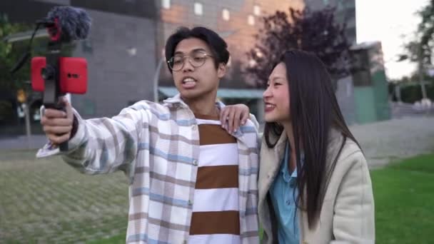 शहर में मोबाइल फोन पर सोशल मीडिया ऐप के लिए वीडियो फिल्माने वाले दो एशियाई किशोर प्रभावशाली व्लॉगर दोस्त — स्टॉक वीडियो