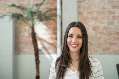Portrait of young woman creative professional employee in a modern office with brick walls doing internship in business company
