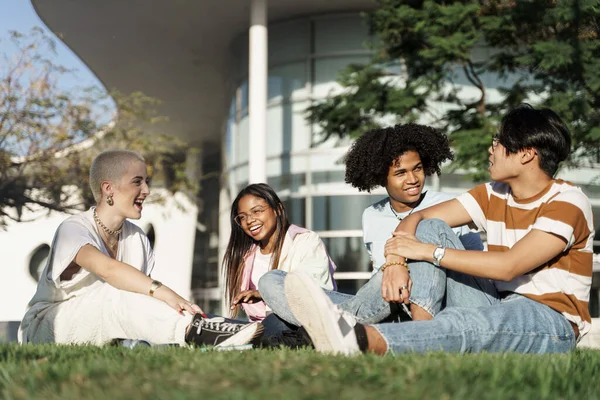 Group of multiracial teenager student friends sitting on the grass in the city park — kuvapankkivalokuva