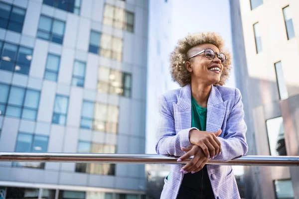 Young African American business woman in trendy outfit and eyeglasses standing on corporate urban district. Creative female professional in the city — kuvapankkivalokuva