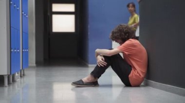 Sınıf arkadaşları onu görmezden gelirken, yerde tek başına oturan üzgün bir genç. Zorbalık gören öğrenci ağlıyor ve depresyona giriyor. Eğitimde Sorun
