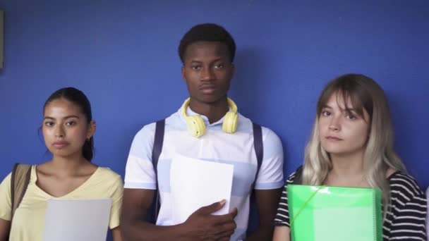 Group of multiracial diverse teenager student friends looking to camera standing over blue wall in the Secondary School College. Diversity in Education and Society — Wideo stockowe