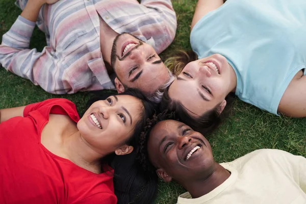 Jeunes amis souriant couchés ensemble sur l'herbe dans le parc. Focus sur Latin American Girl — Photo