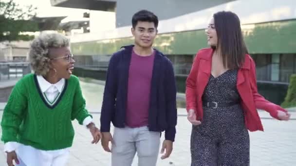 Τρεις μοντέρνοι πολυεθνικοί νεαροί φίλοι περπατούν, απολαμβάνοντας μια συζήτηση μαζί στην πόλη — Αρχείο Βίντεο