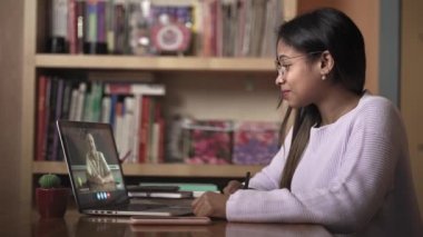 Afrikalı Amerikalı genç kız, Latin kız üniversite öğrencisi web kamerasından öğretmenle bilgisayar eğitimi kursuna bakarak online webinar kursunu izlemeyi öğreniyor.