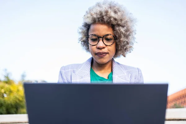 Fokusert ung afrikansk kvinnelig forretningskvinne som jobber med en bærbar datamaskin som skriver e-post – stockfoto