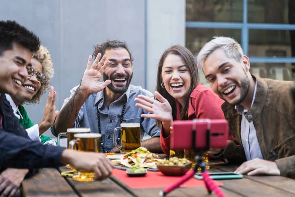 Gruppe av unge venner gjør Video Call i utendørs bar. Vakre unge mangfoldige mennesker drikker øl – stockfoto