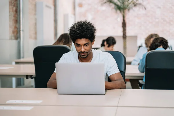 Selvsikker svart mann som jobber på datamaskin i et romslig, moderne kontor – stockfoto