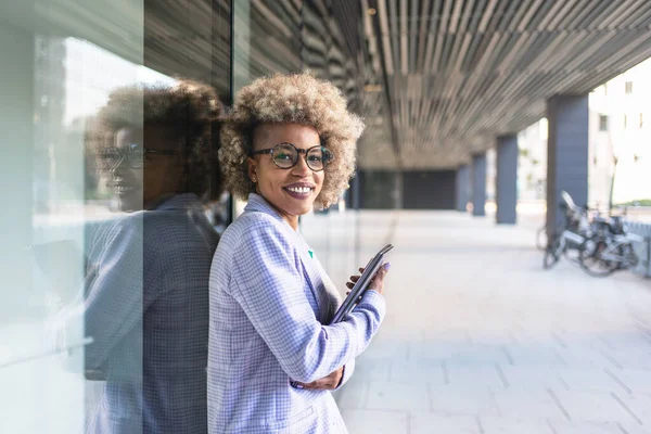 Ung svart forretningskvinne i et nytt kreativt, moderne firma som står utendørs og holder en bærbar datamaskin. – stockfoto