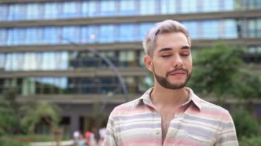 Şehirde yürüyen, kendine güvenen, göz makyajlı genç bir gay portresi.