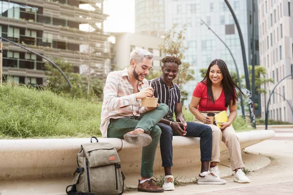 Heureux jeunes amis profiter du temps ensemble et manger à emporter de la nourriture en plein air dans la ville — Photo