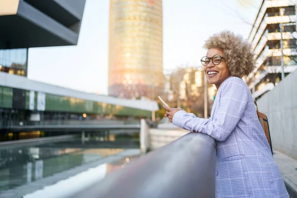 Cheerful professional successful black woman standing in the city after work