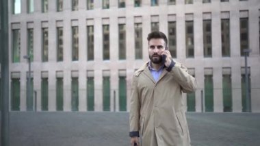 Müşterilerle görüşmeye giderken cep telefonuyla konuşan ciddi bir iş adamı. Önemli bir konuşma için şehirdeki genç trend yöneticisi