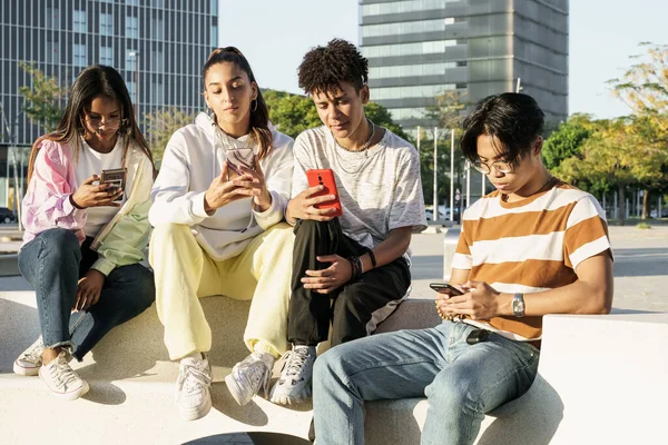 Gruppo di amici seduti insieme utilizzando i loro telefoni cellulari — Foto Stock