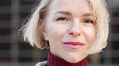 Zarif, şık, Ukraynalı sarışın bir kadının ciddi bir ifadeyle kameraya bakışının yakın portresi.