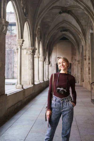Muotokuva vaalea nainen turisti vintage kamera vierailevat antiikin luostarin kirkko Euroopassa — kuvapankkivalokuva