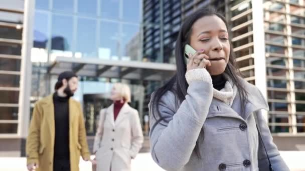 Czarna, profesjonalna kobieta rozmawiająca przez telefon komórkowy. Ludzie biznesu spieszący się do pracy na zewnątrz — Wideo stockowe