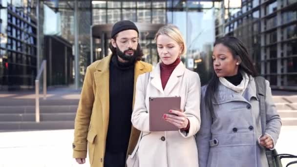 Drie collega 's uit het bedrijfsleven praten over het project, gebruiken digitale tablet en lopen buiten het kantoor — Stockvideo