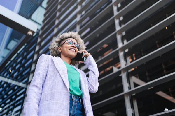 Selvsikker, kul, svart forretningskvinne som snakker i telefonen utenfor en moderne bygning. Yrke for unge kvinner på vakt. – stockfoto