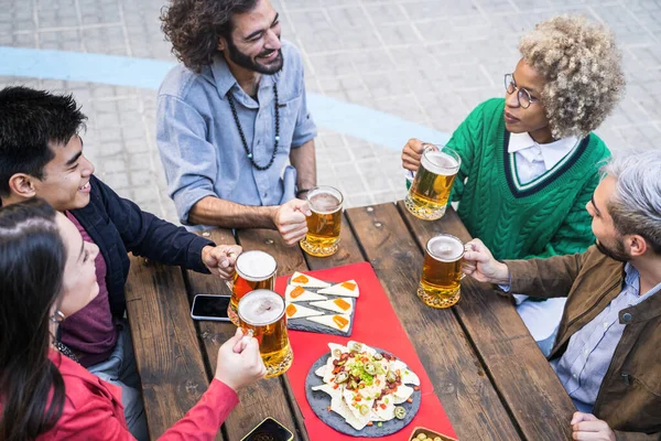 Jonge vrienden genieten samen van een drankje en eten in de buitenbar in de stad — Stockfoto