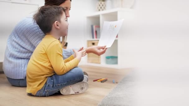 Kindertherapeut helpt kind om gezinsproblemen te begrijpen door een tekening van zijn ouders te maken. Geestelijke gezondheidstherapie voor kinderen — Stockvideo